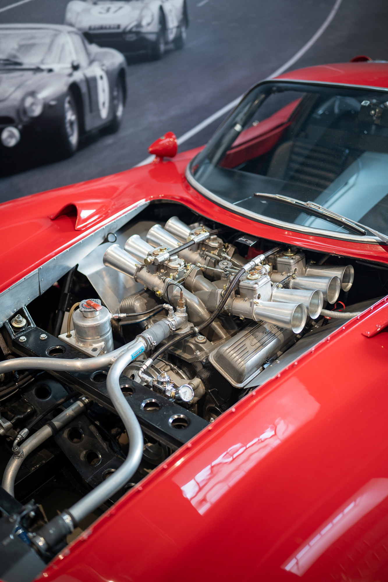 Close-up of the red classic race car's V8 engine with quad Weber carburetors and racing livery.