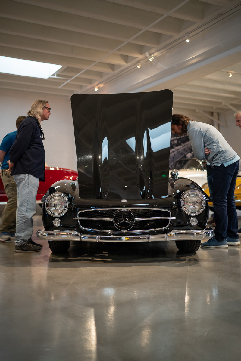 Front view of a black Mercedes-Benz 300 SL Gullwing with hood open at a car show.