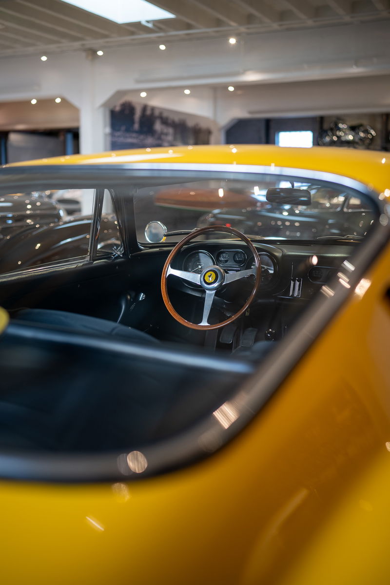 Interior view of a yellow Ferrari, showcasing its classic wood-rimmed steering wheel.