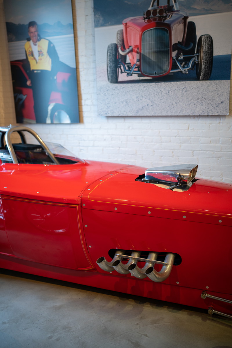 Red dragster with chrome scoop and zoomie exhaust pipes.