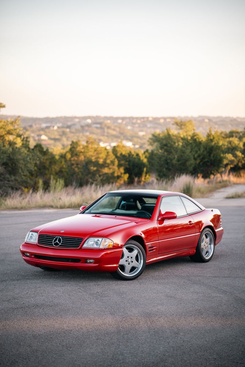 A red 2001 Mercedes-Benz SL600 with chrome rims parked on asphalt.