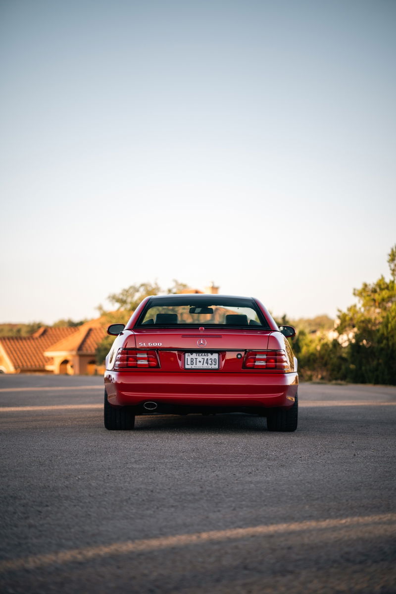 Red 2001 Mercedes-Benz SL600 rear view with clear tail lights and chrome trim.