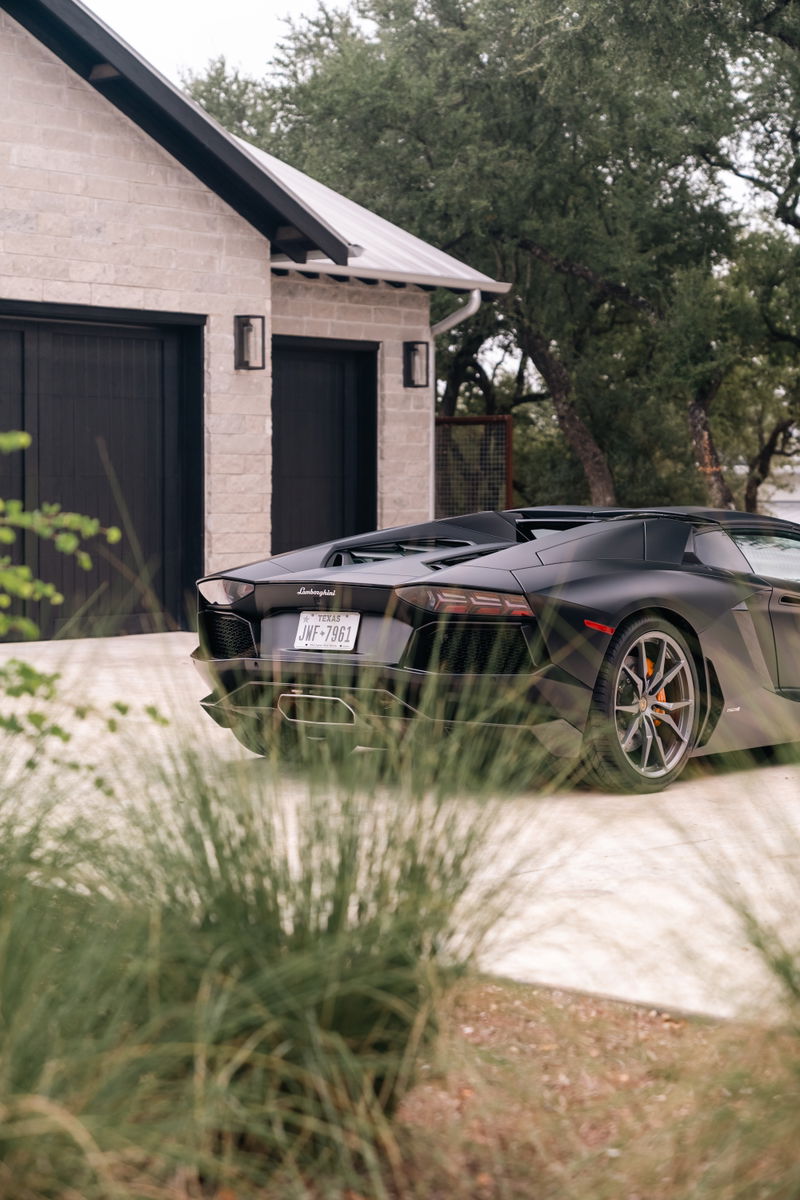 Black Lamborghini Aventador LP700-4 rear-view showing its multi-spoke rims and aggressive styling.