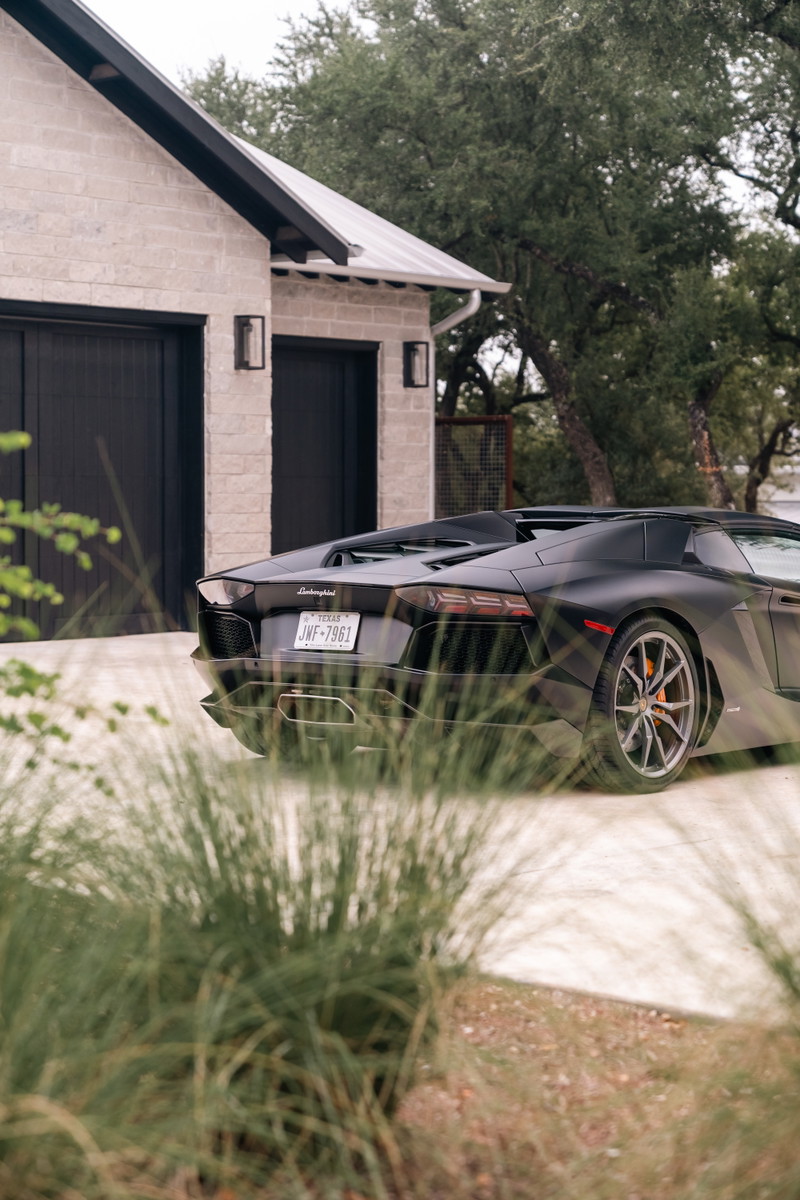 Black Lamborghini Aventador LP700-4 rear-view showing its multi-spoke rims and aggressive styling.