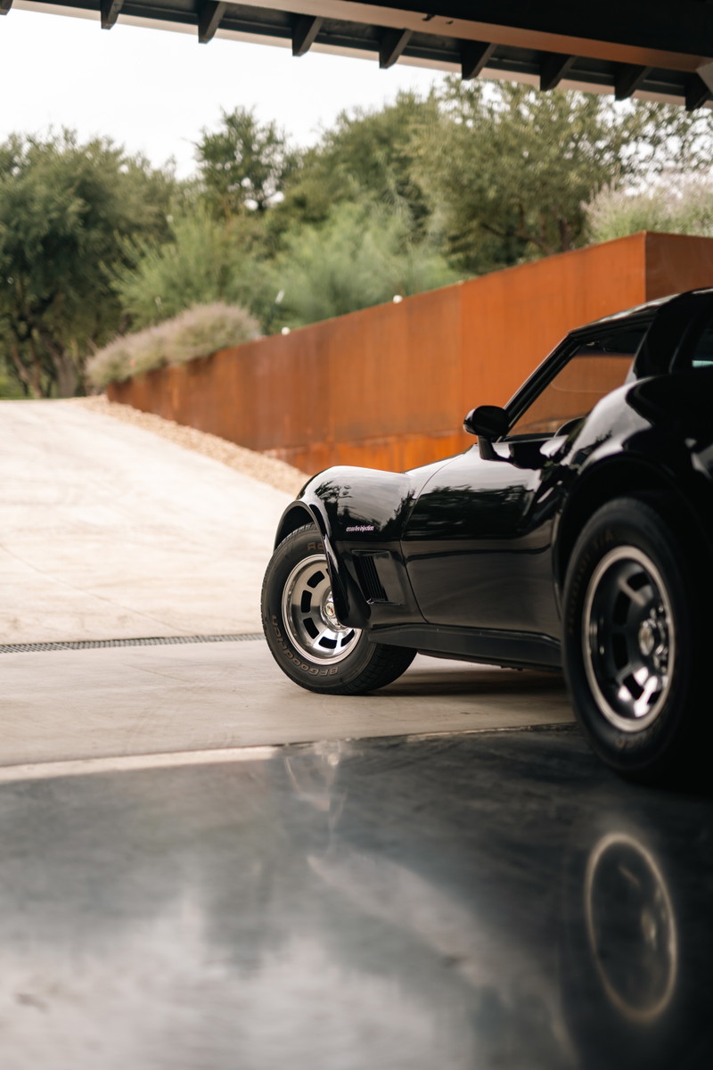 Black 1982 Chevrolet Corvette Stingray with classic rims, parked in a garage.