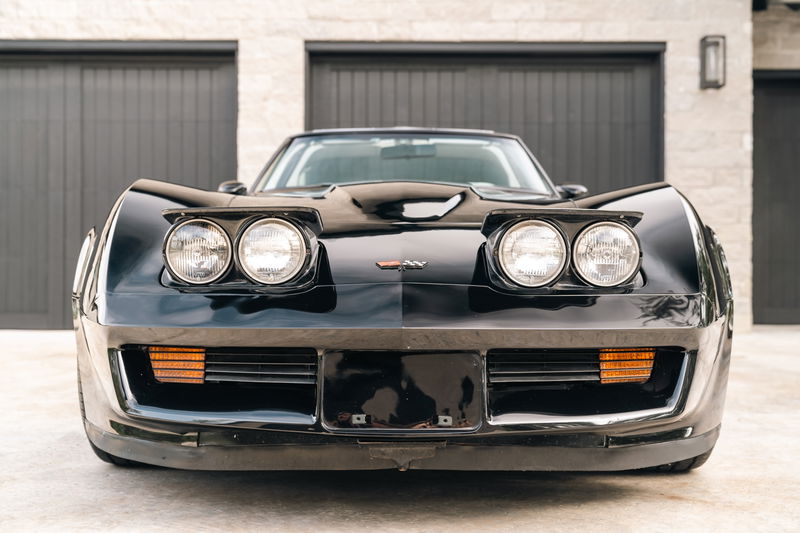 Front view of a black 1982 Corvette Stingray, featuring pop-up headlights and amber turn signals.