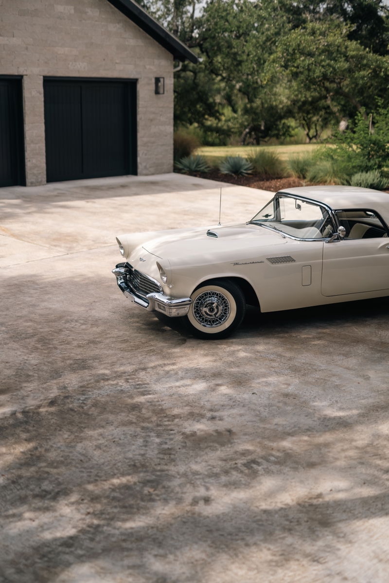 A colonial white 1957 Ford Thunderbird convertible with wire wheel rims.