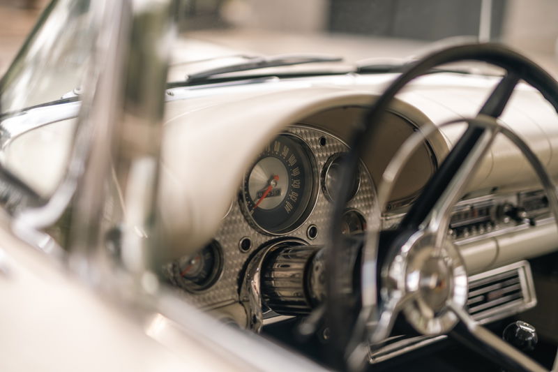 Close-up of a 1957 Ford Thunderbird dashboard, featuring a vintage steering wheel and chrome trim.