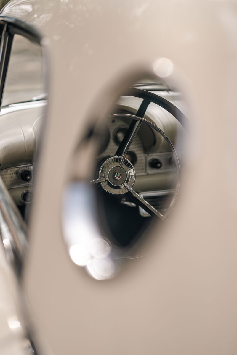 Close-up interior shot of a white 1957 Ford Thunderbird's steering wheel and dashboard.