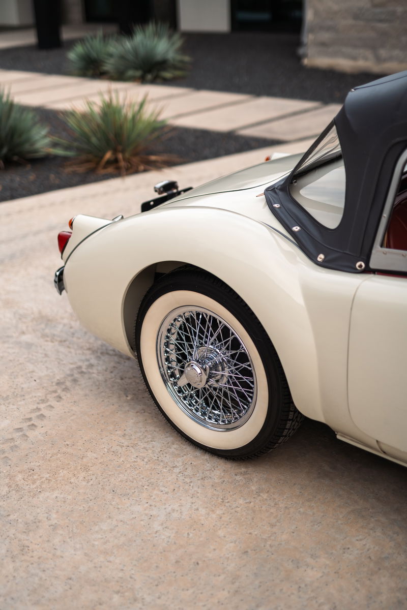 Cream 1957 MG MGA features chrome wire rims and whitewall tires.