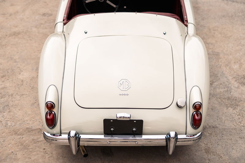 Rear view of a classic white 1957 MG MGA with chrome bumper and trim.