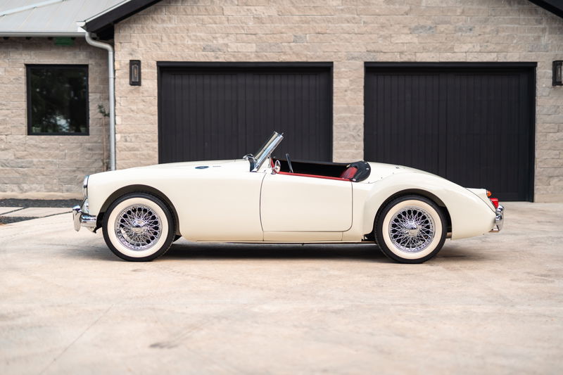 Side profile of a white 1957 MG MGA convertible with wire wheels and red interior.