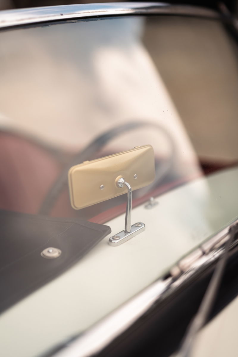 Interior shot of a vintage MGA coupe with a gold rearview mirror and tan dash trim.