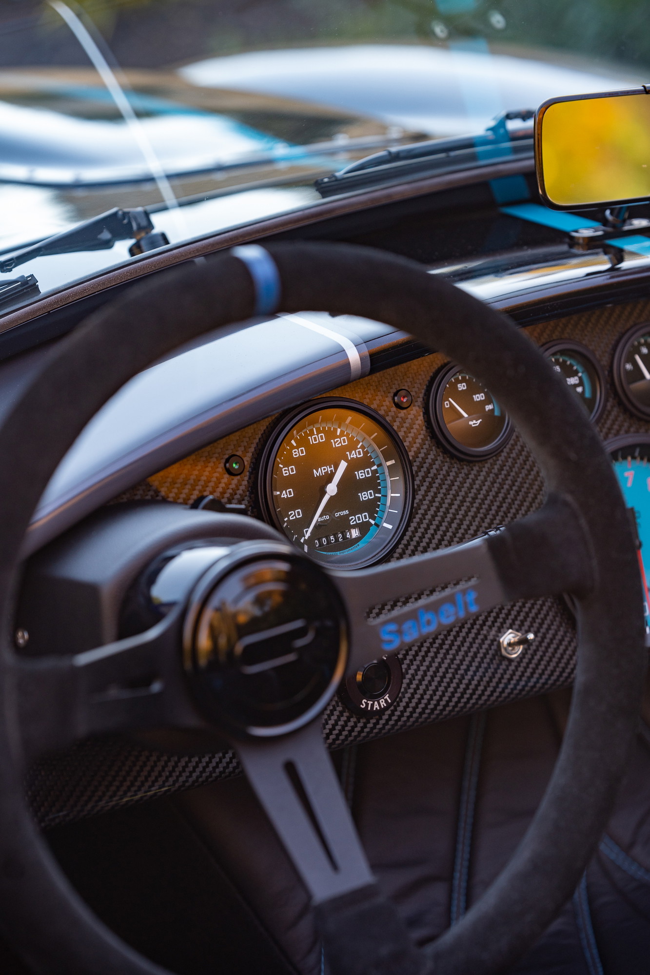Close-up of a 1965 Backdraft Cobra's Sabelt steering wheel and carbon fiber dash.