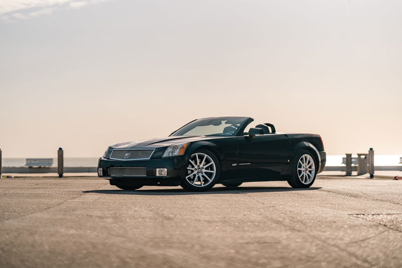 Black Raven 2006 Cadillac XLR-V convertible with chrome rims parked outdoors.