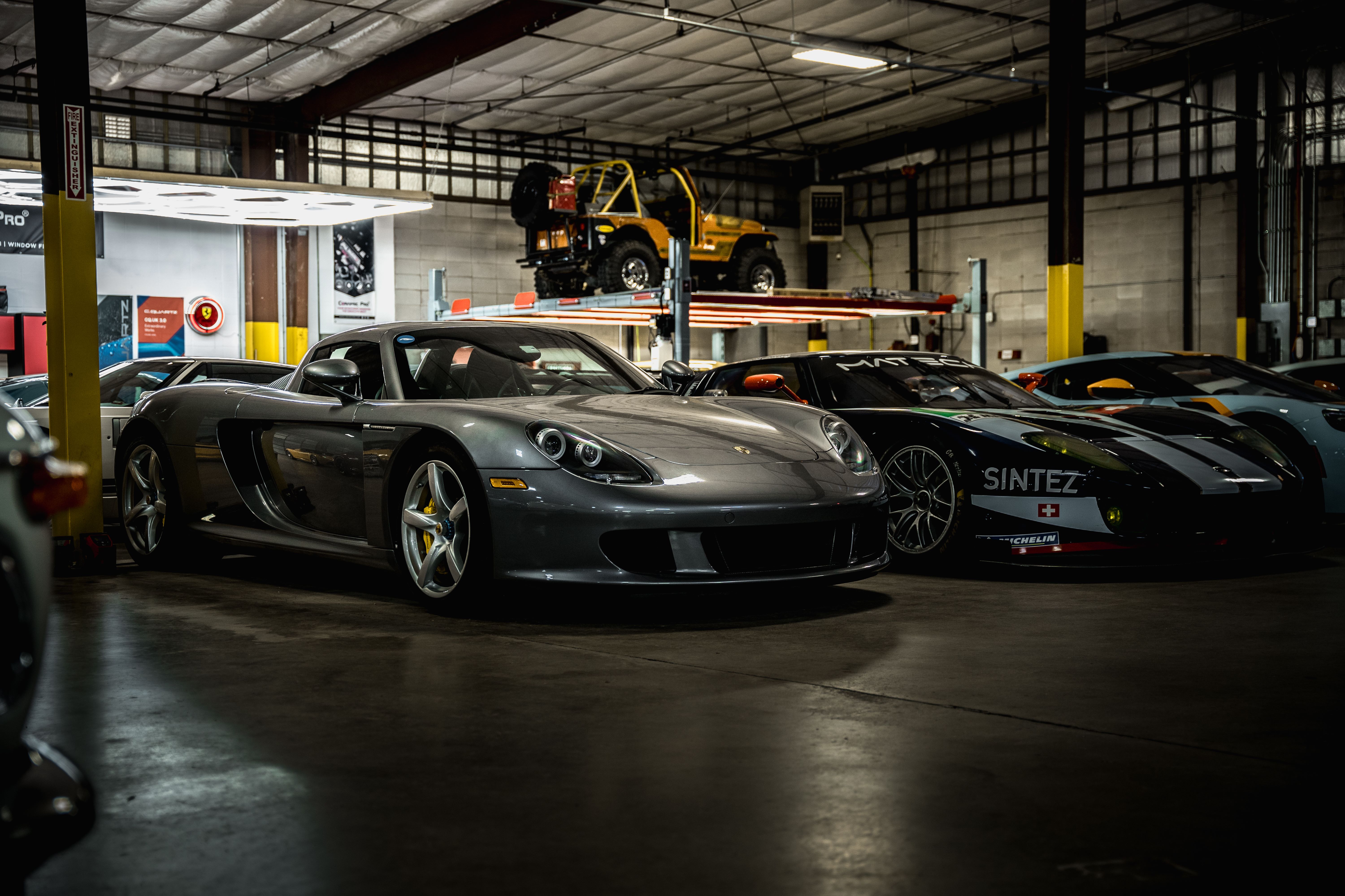 Silver Porsche Carrera GT with yellow brake calipers and grey rims in a garage.