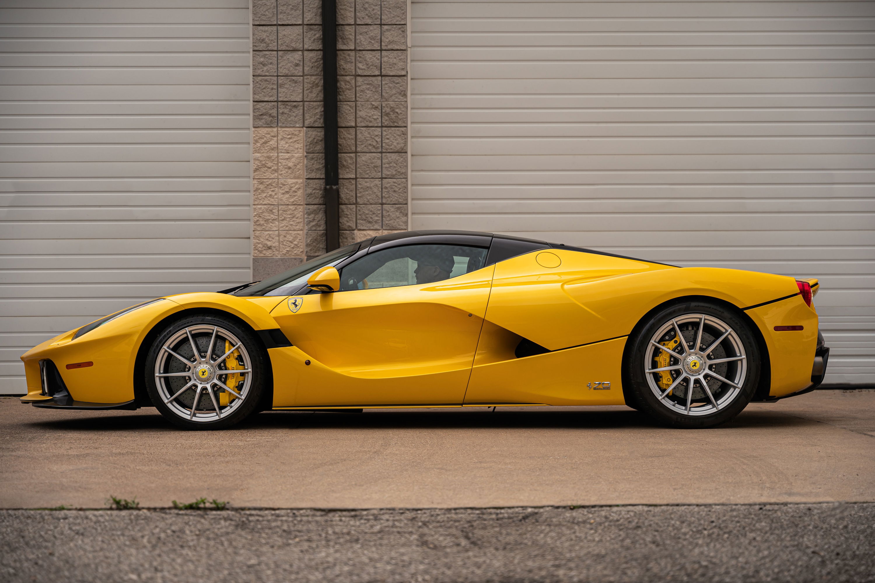 Yellow Ferrari LaFerrari with black roof, silver multi-spoke rims, and yellow brake calipers.
