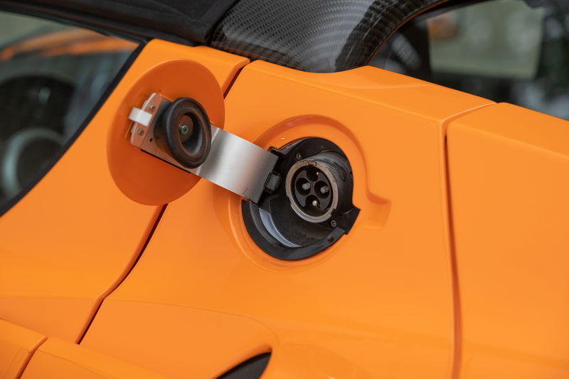 Close-up of the charging port on an orange 2010 Tesla Roadster.