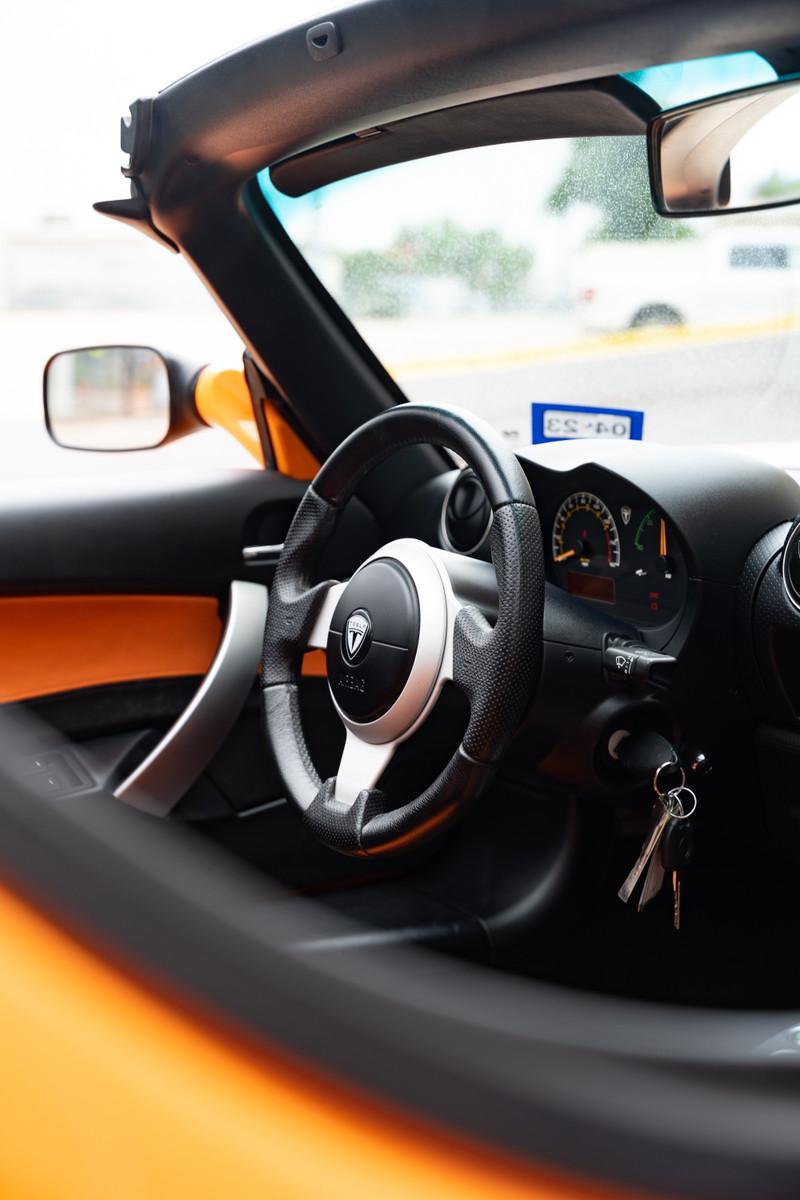 2010 Tesla Roadster interior. Orange trim accentuates the sporty steering wheel and dash.