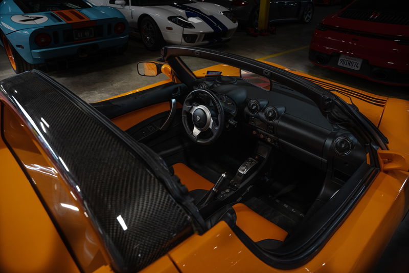 Orange 2010 Tesla Roadster with carbon fiber trim and black interior.