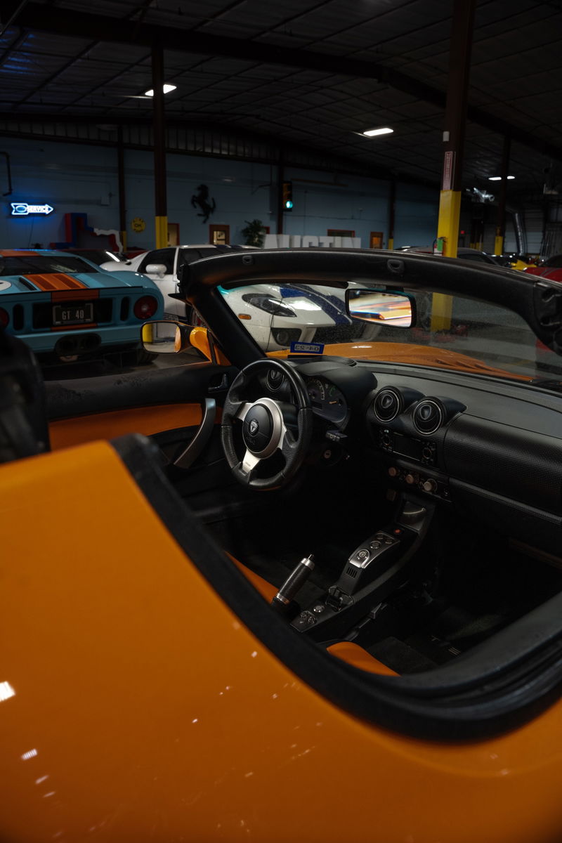 Interior shot of a 2010 Tesla Roadster in metallic orange with black trim and floor shifter.