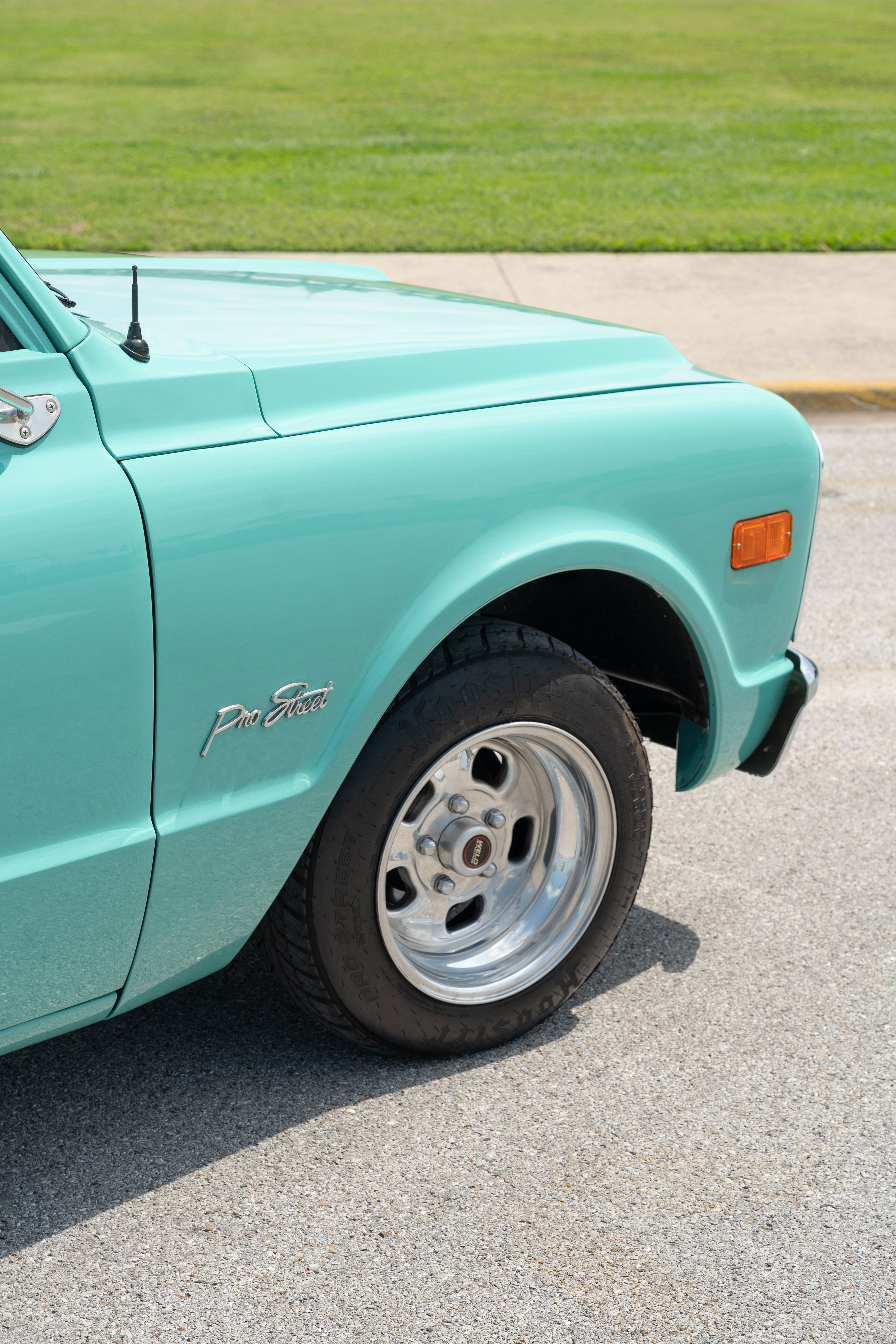 Close-up of a turquoise 1968 Chevrolet C10 Pro Street pickup with chrome rims and fender badging.