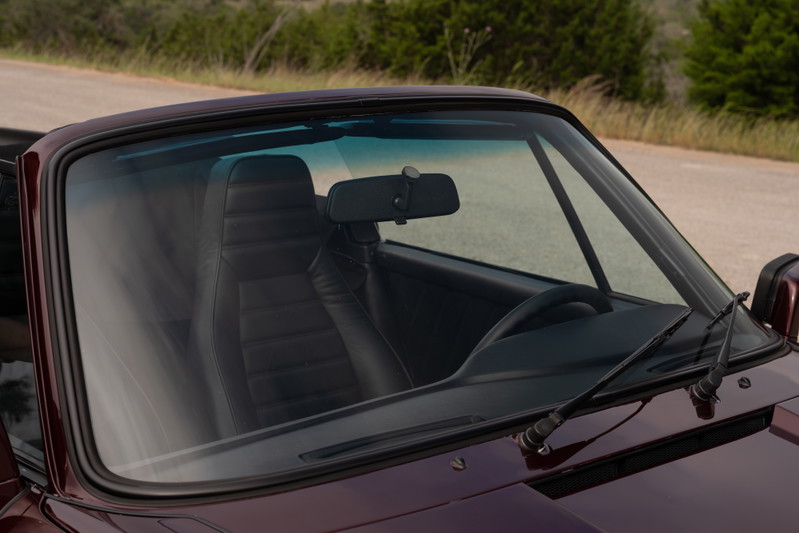 Ruby red metallic 1983 Porsche 911 SC Cabriolet interior, black leather seats, dashboard, steering wheel.