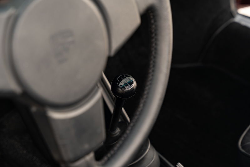 Close-up of a 1983 Porsche 911 SC Cabriolet's manual gear shifter and steering wheel.