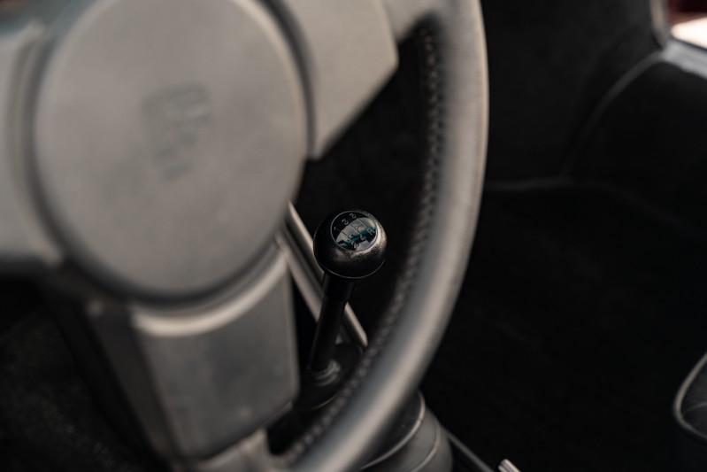 Close-up of a 1983 Porsche 911 SC Cabriolet's manual gear shifter and steering wheel.