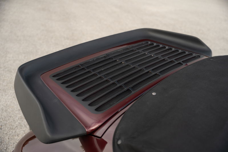 Close-up of a ruby red metallic 1983 Porsche 911 SC Cabriolet rear decklid grille and spoiler.