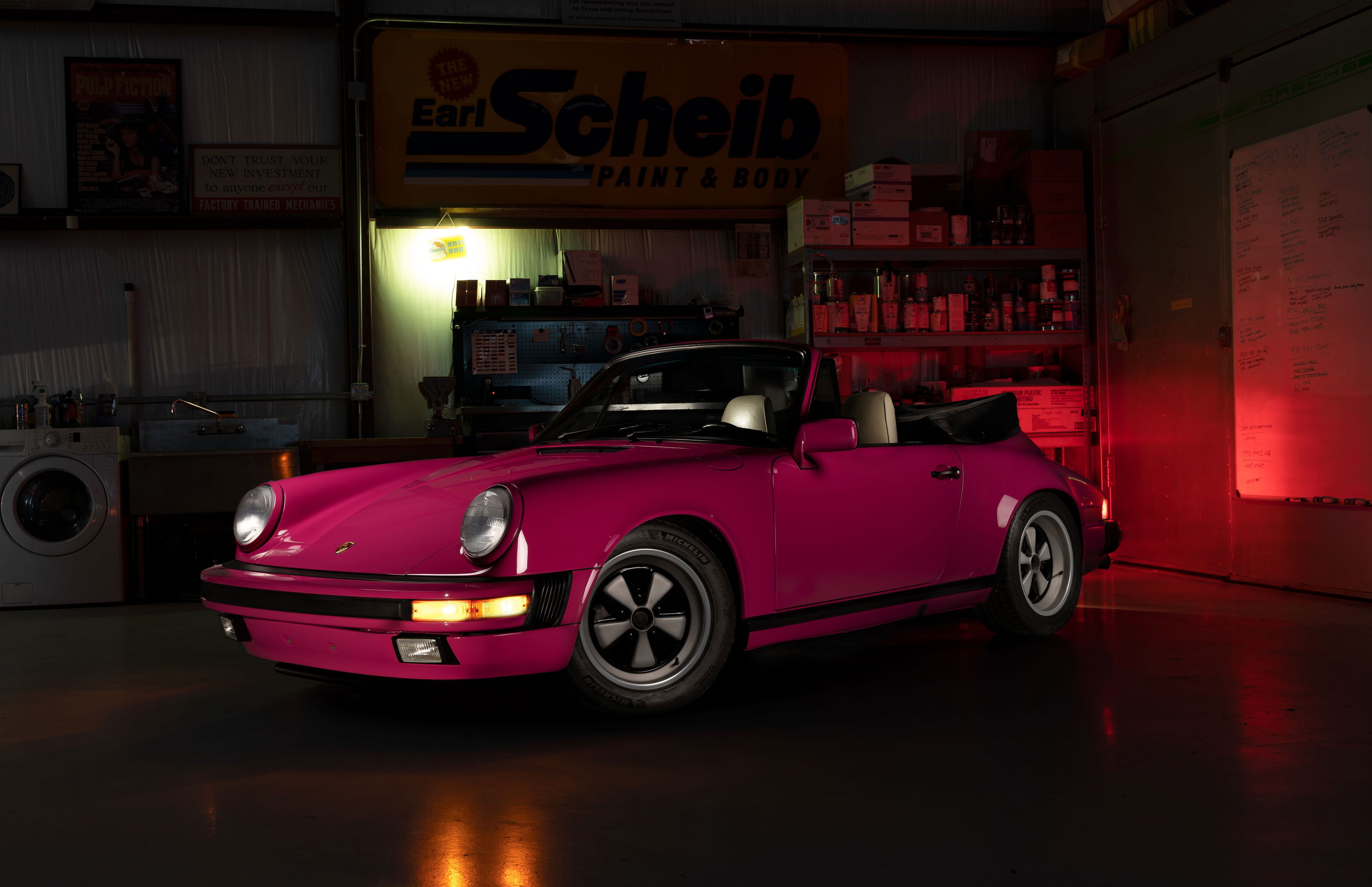 A pink Porsche 911 Targa with Fuchs wheels, parked in a garage.