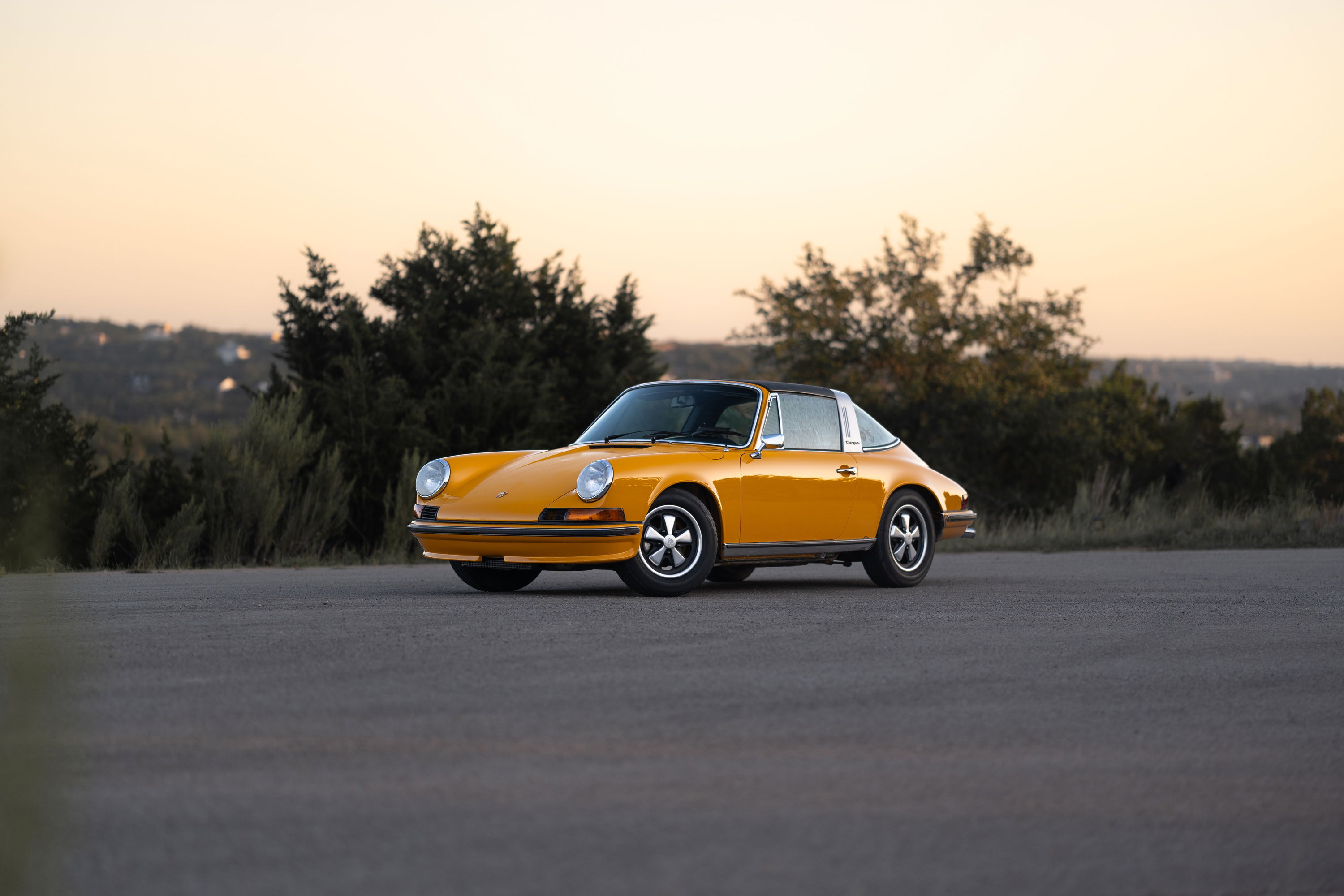Signal yellow 1973 Porsche 911S Targa with chrome trim and Fuchs rims.