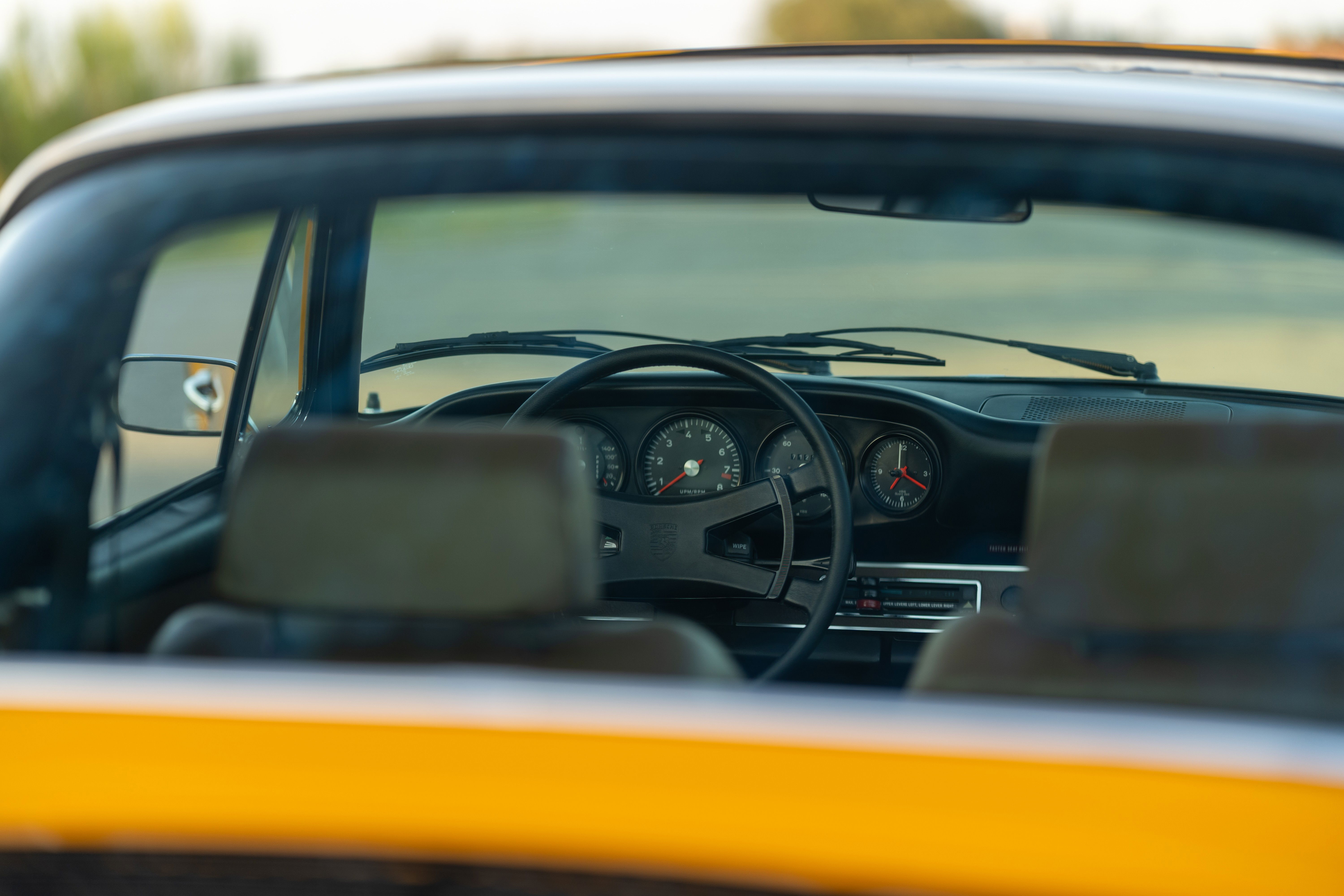 Interior view of a 1973 Porsche 911S Targa, featuring classic gauges and black steering wheel.