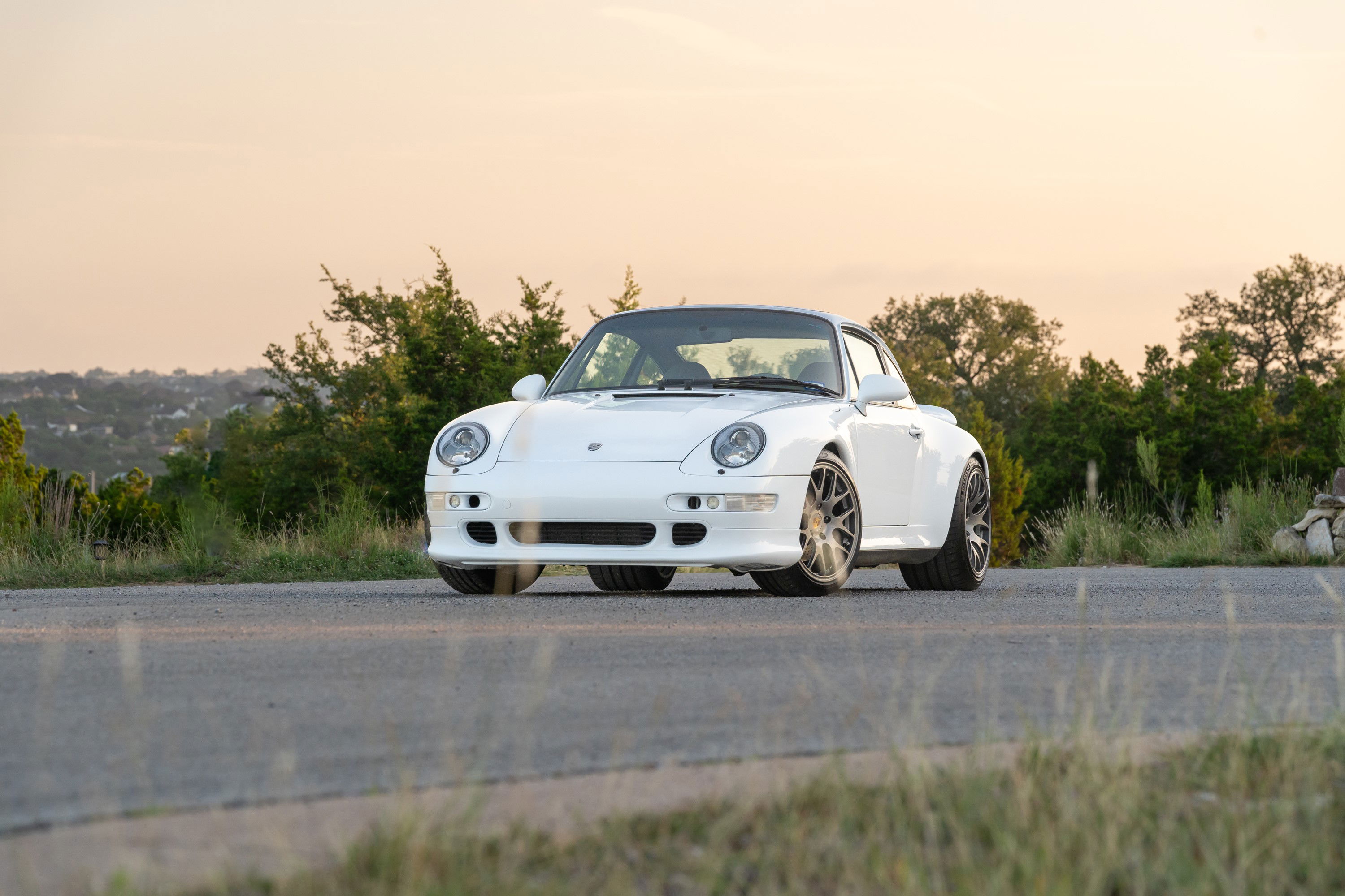 White 1997 Porsche 911 (993) C4S with aftermarket rims parked on a road.