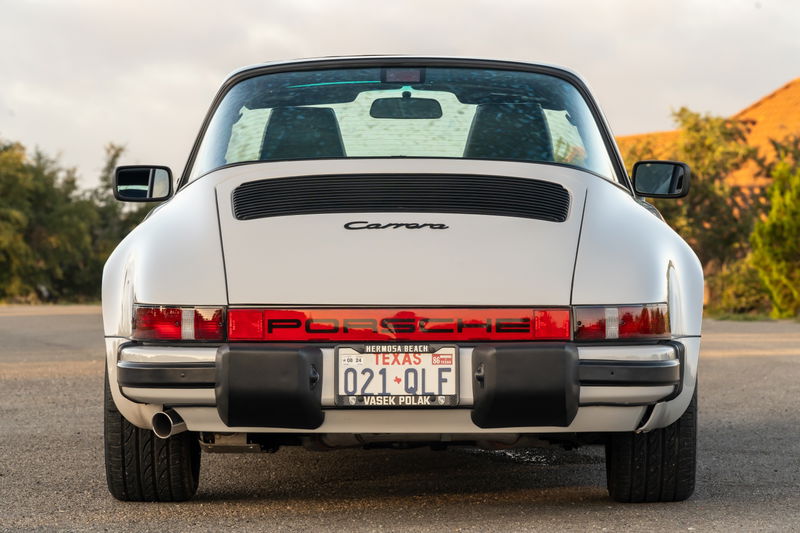 Rear view of a white 1987 Porsche 911 Carrera Targa with "PORSCHE" and "Carrera" badging.