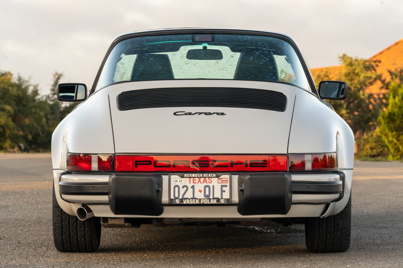 Rear view of a white 1987 Porsche 911 Carrera Targa with "PORSCHE" and "Carrera" badging.
