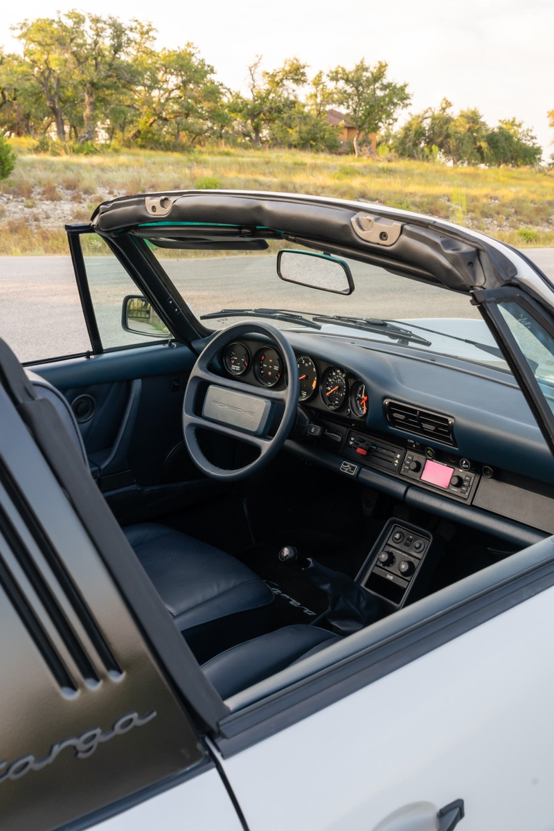 Interior view of a white 1987 Porsche 911 Carrera Targa with blue leather seats and dashboard.