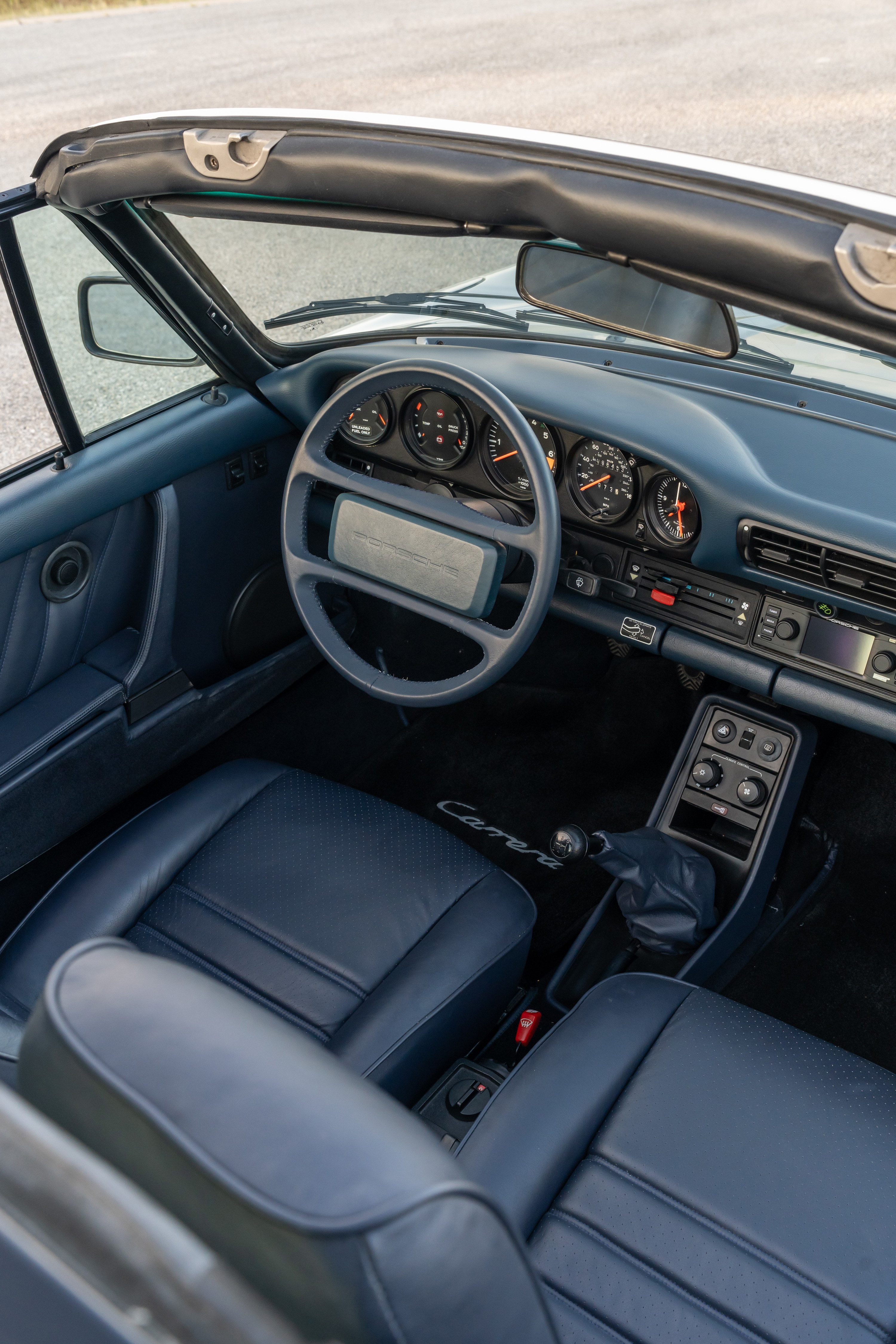 Interior view of a 1987 Porsche 911 Carrera Targa in Marble Grey with blue leather seats and dashboard.
