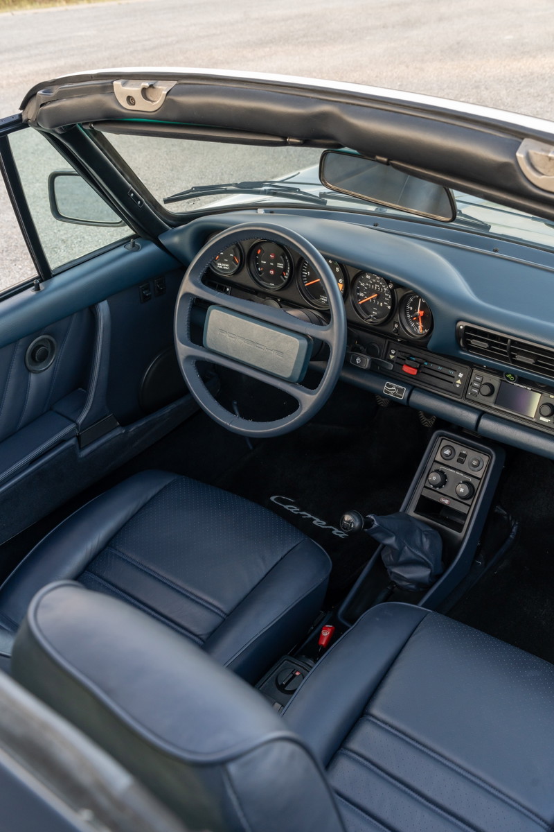 Interior view of a 1987 Porsche 911 Carrera Targa in Marble Grey with blue leather seats and dashboard.