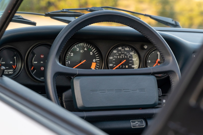 Interior dashboard of a Marble Grey 1987 Porsche 911 Carrera Targa with classic gauges.