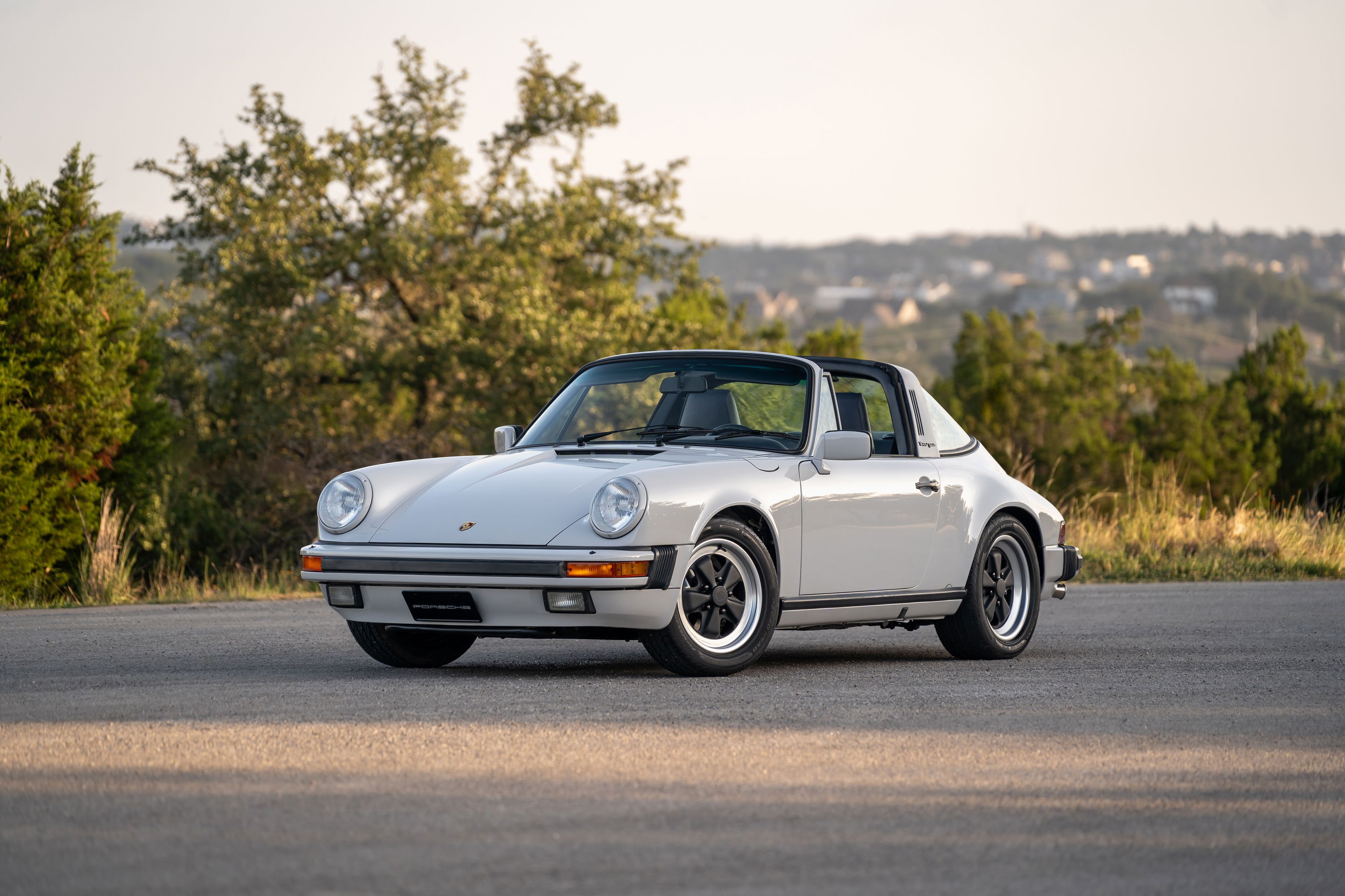 A 1987 Porsche 911 Carrera Targa in Marble Grey. Features Fuchs wheels and a Targa top.