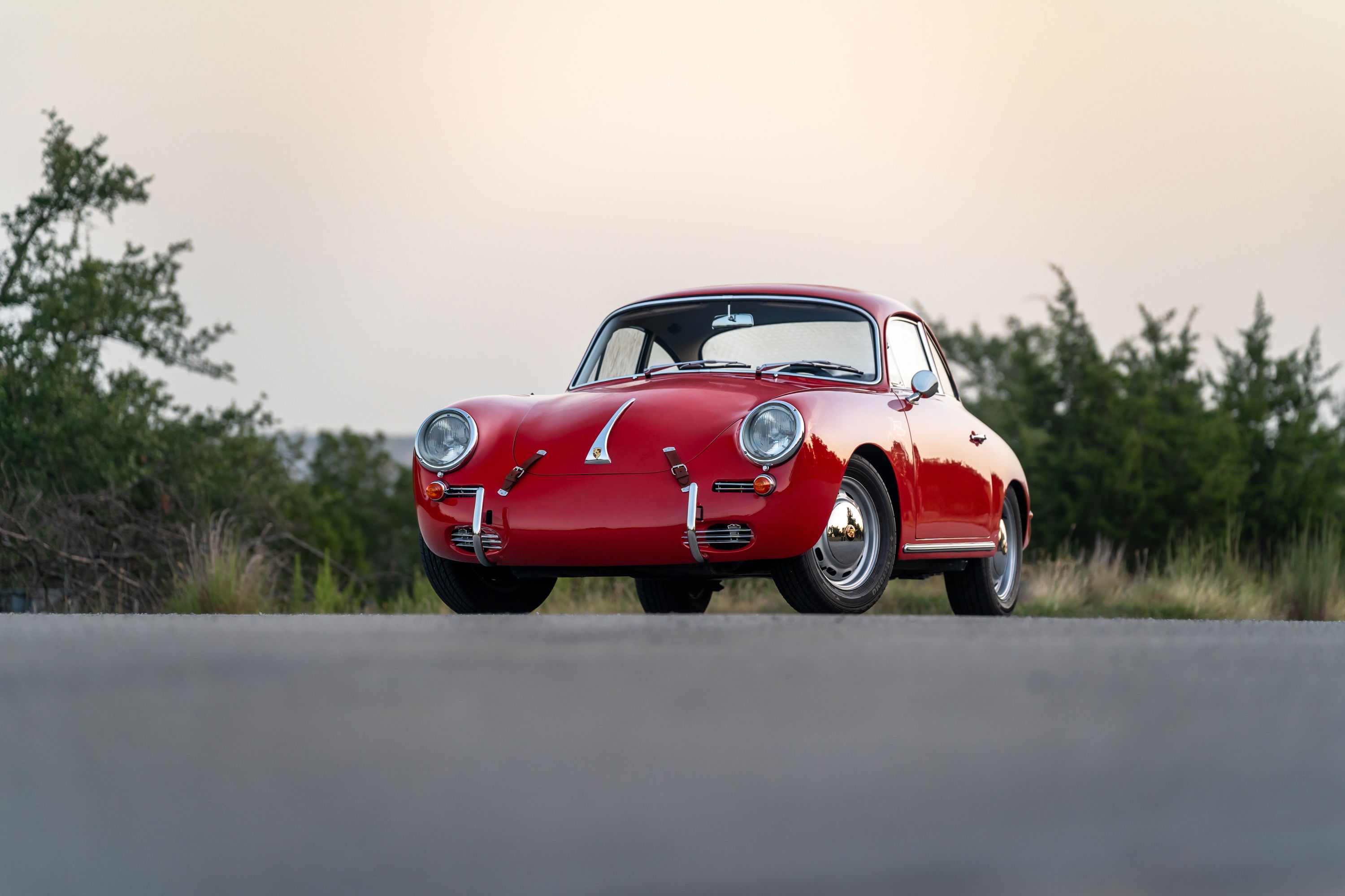 A red 1965 Porsche 356C coupe with chrome rims and trim.
