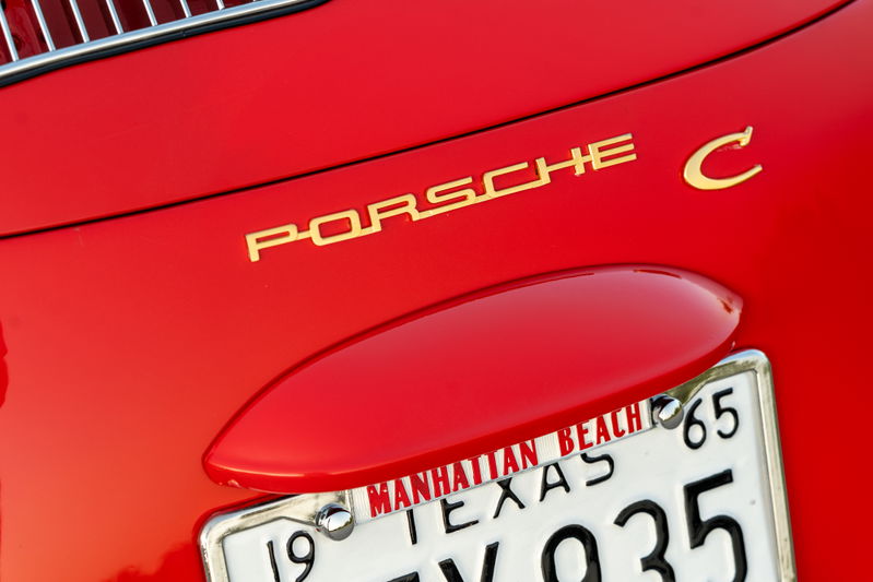 Golden "Porsche C" emblem on a Signal Red 1965 Porsche 356C with a Texas license plate.