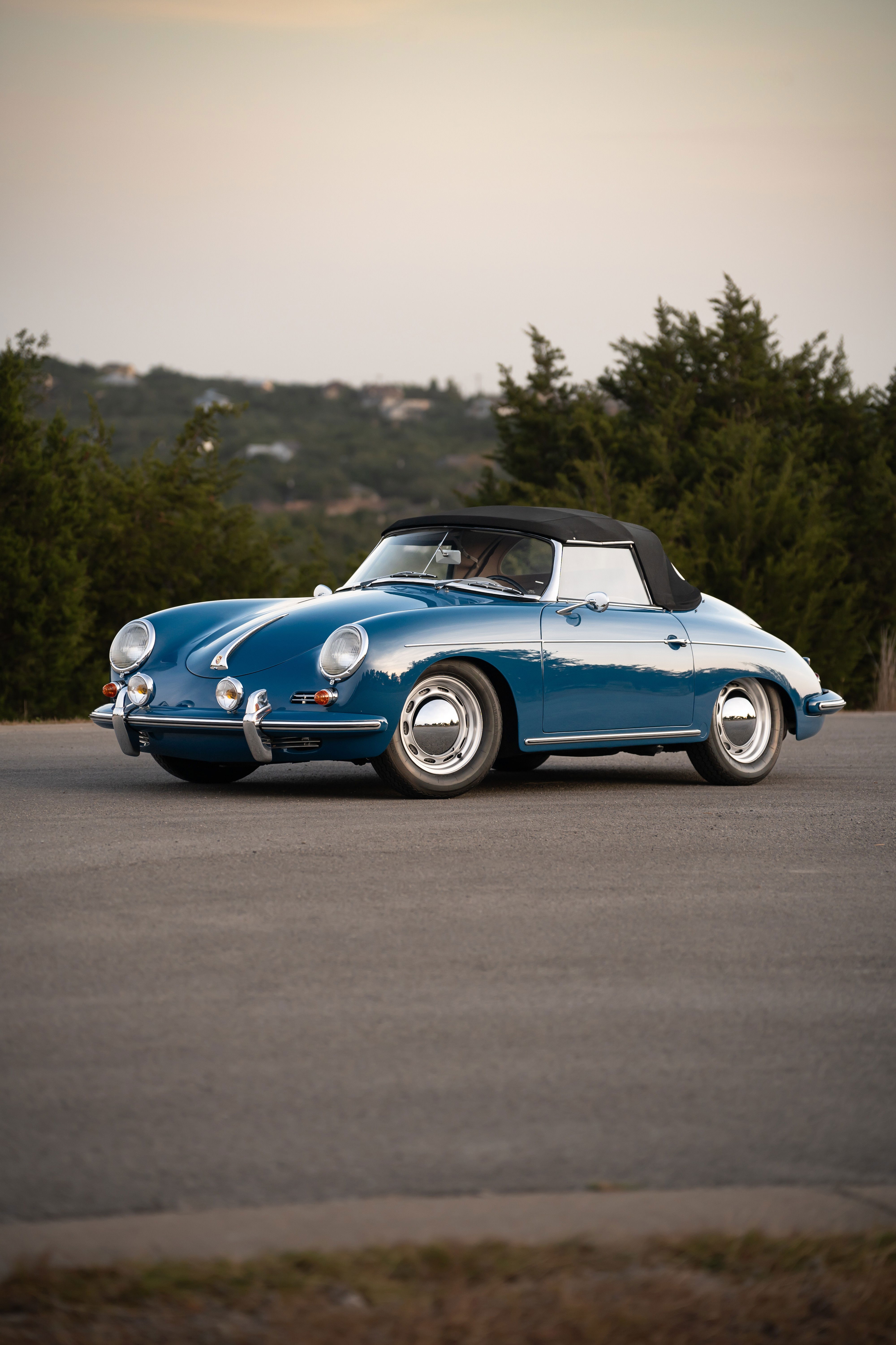 Blue 1960 Porsche 356B Roadster with chrome hubcaps and white stripe livery.