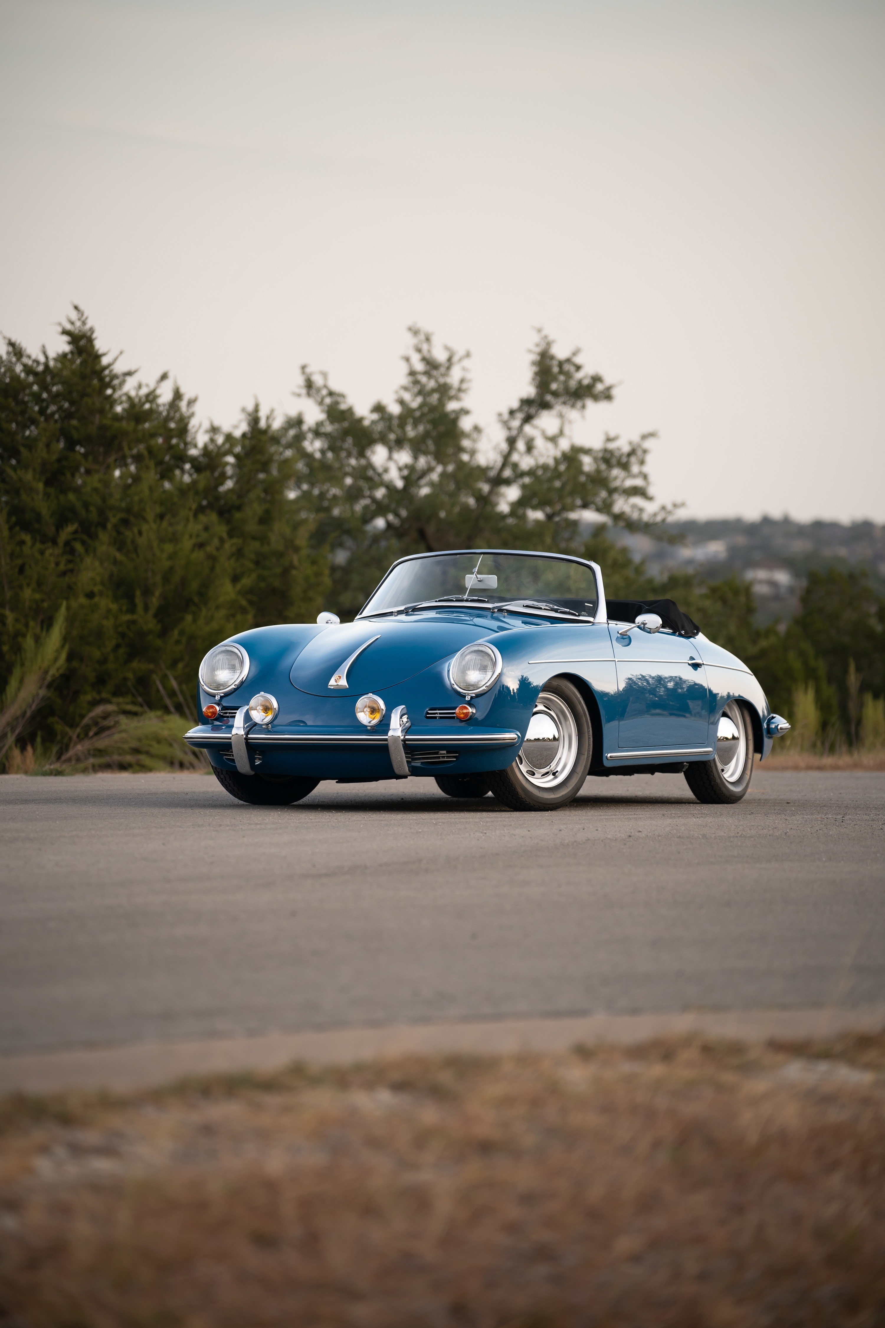 A royal blue 1960 Porsche 356B Roadster convertible with chrome trim and wire wheels.