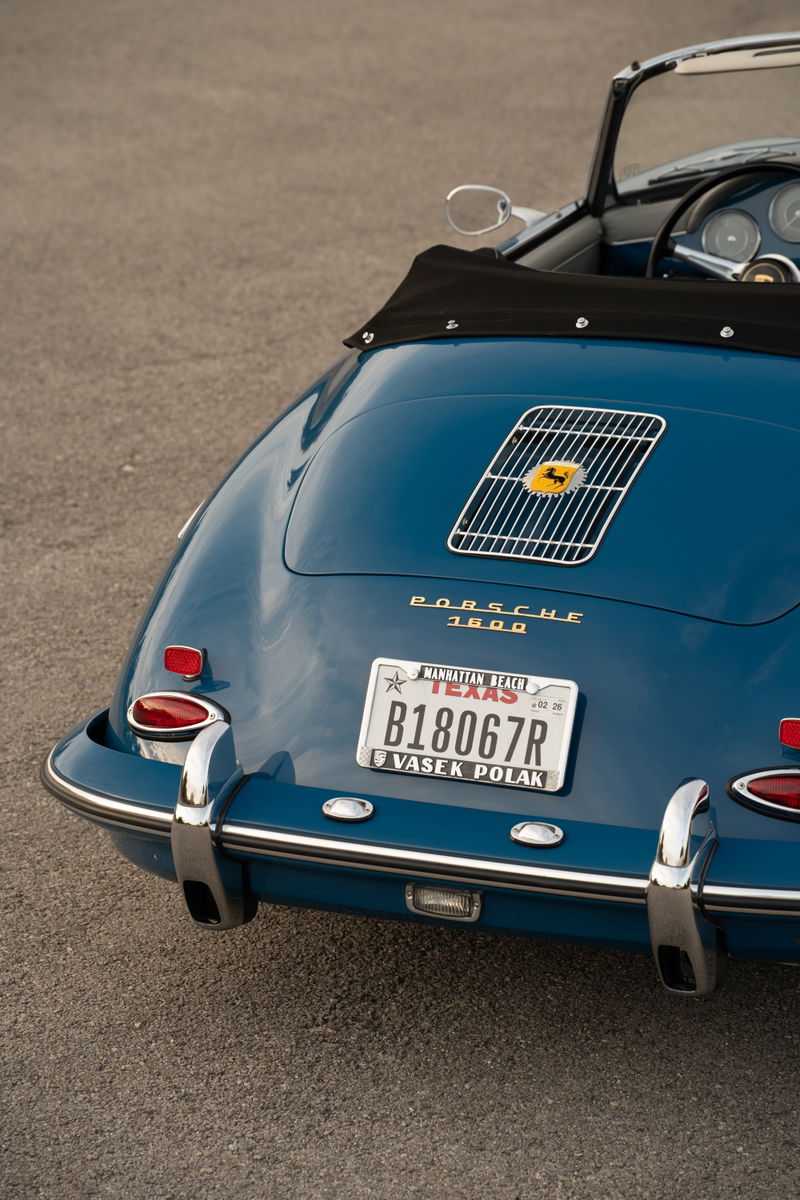 Rear view of a Royal Blue 1960 Porsche 356B Roadster with chrome bumpers and a yellow Porsche badge.