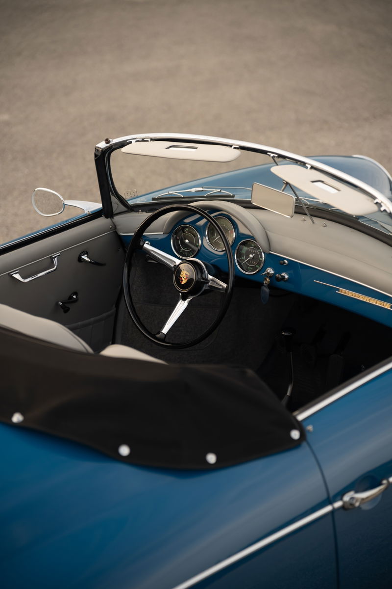 Interior of a royal blue 1960 Porsche 356B Roadster, featuring a classic steering wheel and dashboard.
