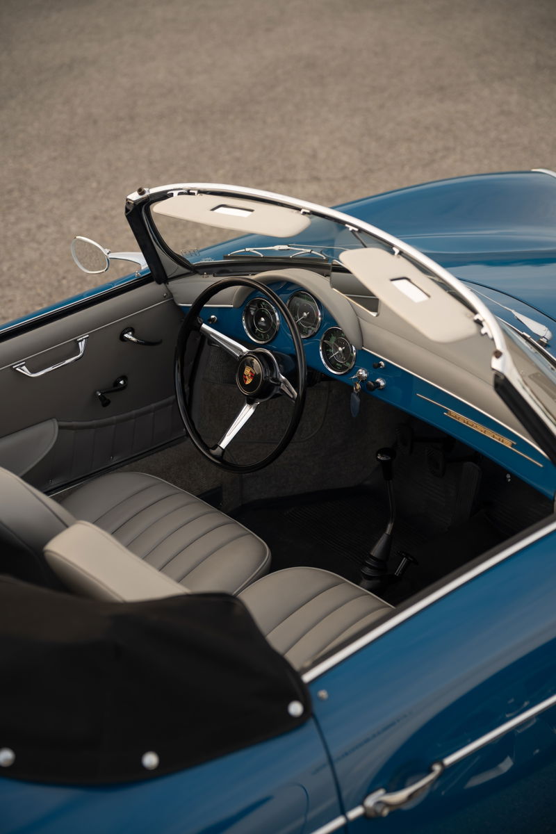 Interior view of a royal blue 1960 Porsche 356B Roadster, featuring classic gauges and grey leather seats.