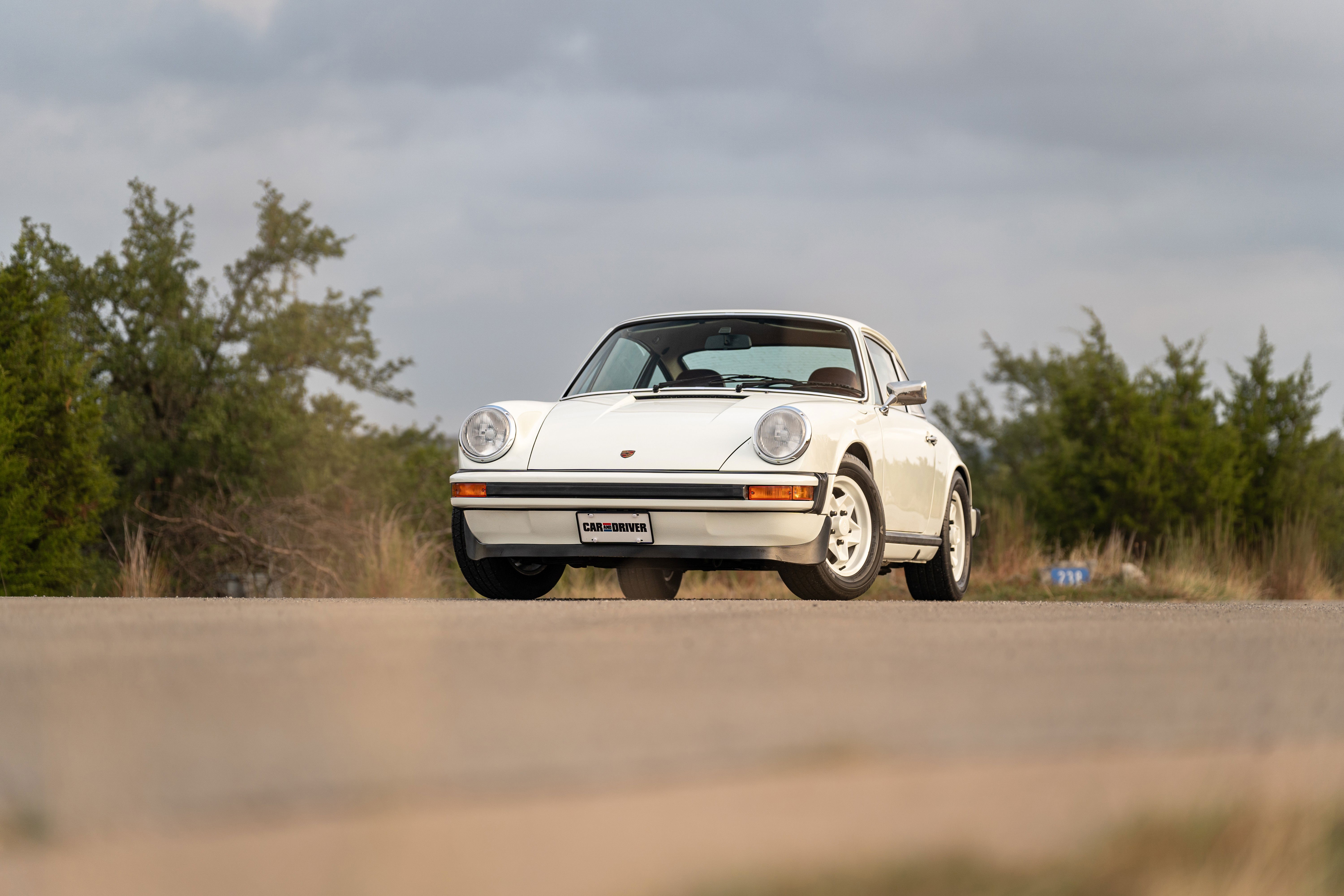 1974 Porsche 911 coupe in white with silver Fuchs rims, chrome trim, and factory livery.
