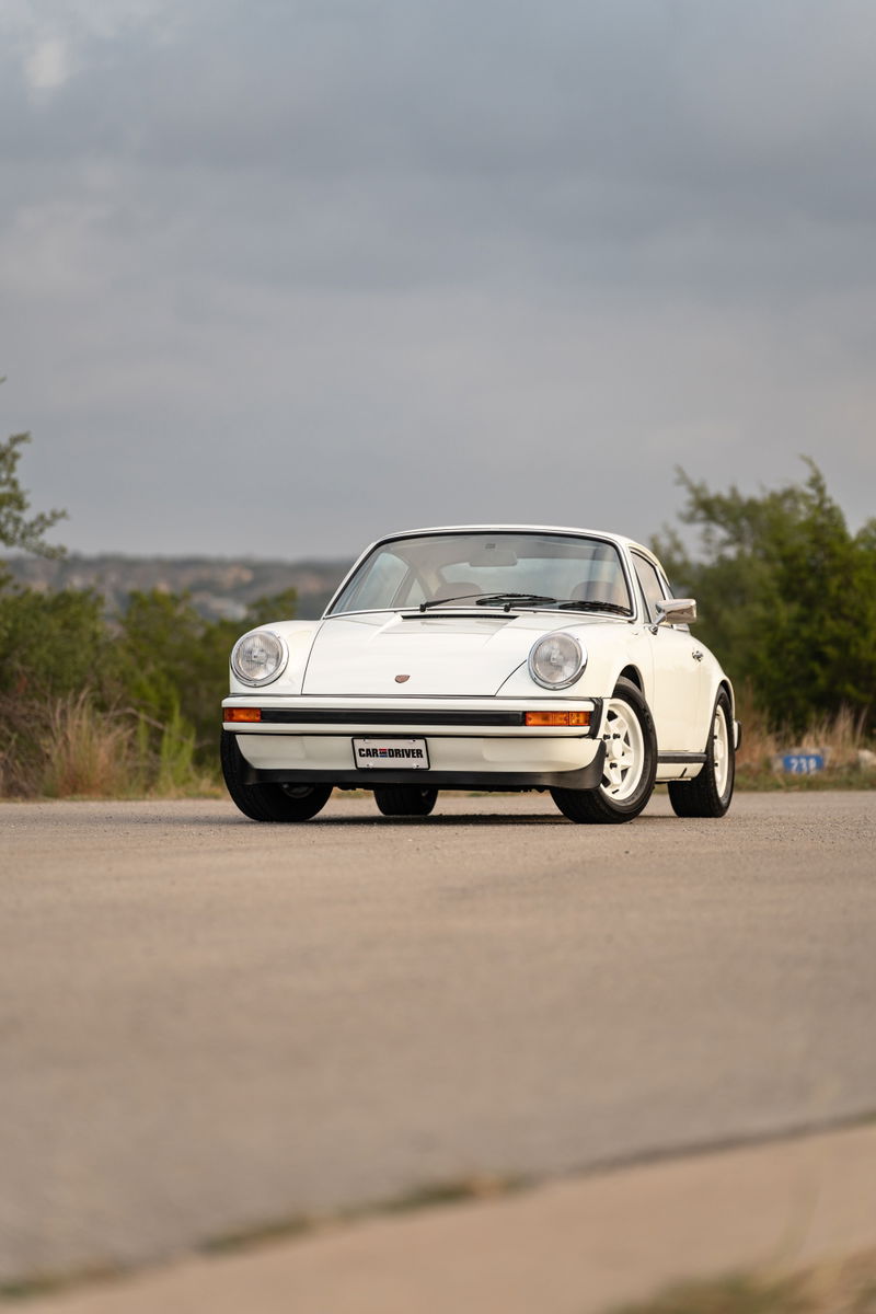 A white 1974 Porsche 911 coupe with chrome trim and turbines rims.